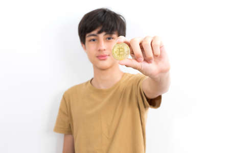 Teenage boy holds a bitcoin on a white isolated background.の写真素材