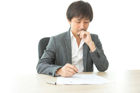 Middle age Asian businessman writing document report on the desk in the office. Signing contract.の写真素材