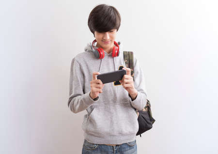 European teen boy student texting or playing game online on smartphone isolate on white background.の写真素材