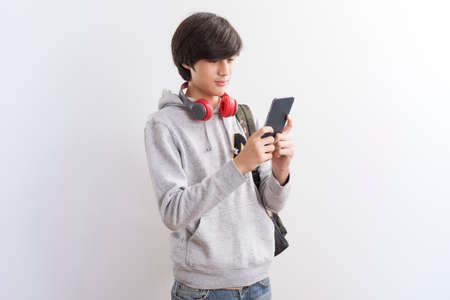 European teen boy student texting or playing game online on smartphone isolate on white background.の写真素材