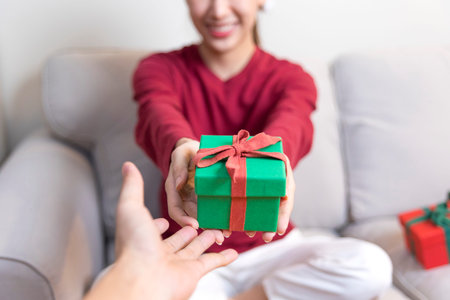 Christmas Gift in hands. Happy woman giving Christmas and New Year Gift box to man at Home. Family...