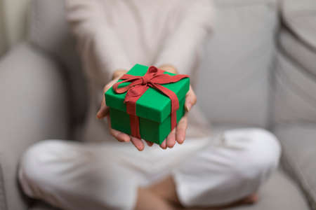 Christmas Gift in hands. Happy woman giving Christmas and New Year Gift box to man at Home. Family X'mas celebration. Person Holding, Receiving a Gift box.の写真素材