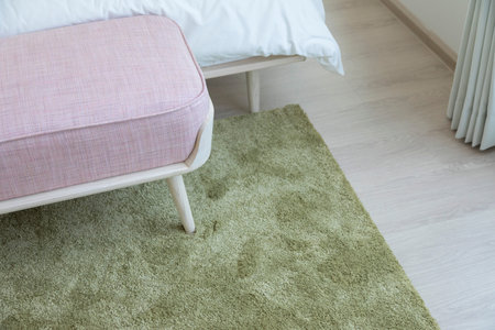 Close up of carpet by the bed, close up near the bed and the bench.