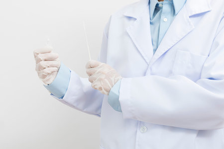 Medical personnel holding Antigen Test Kit (ATK) standing on white background.