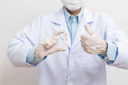 The doctor showing Covid-19 negative test result of the antigen rapid test kit on white background,Coronavirus infectious protect concept.の写真素材