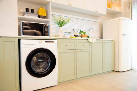 Modern green kitchen interior with washing machine and microwave.の写真素材