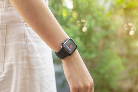 Close up of young woman looking on her smartwatch in the green garden background