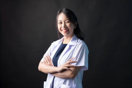 Young Asian female physician, Med student or resident doctors standing and smile on black background.の写真素材