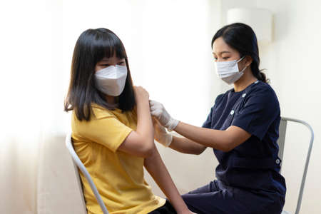Asian Preteen Girl Getting Vaccinated, Receiving Coronavirus Vaccine Injection in clinic.の写真素材