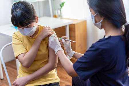 Asian Preteen Girl Getting Vaccinated, Receiving Coronavirus Vaccine Injection in clinic.の写真素材