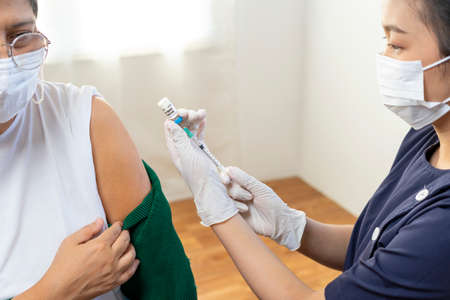 Elderly Asian woman getting coronavirus vaccine by nurse. Medical worker prepare syringe.の写真素材