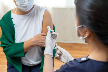 Elderly Asian woman getting coronavirus vaccine by nurse. Medical worker prepare syringe.の写真素材