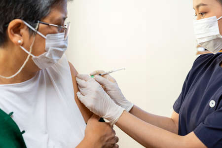Elderly Asian woman getting coronavirus vaccine by nurse. Medical worker prepare syringe.の写真素材