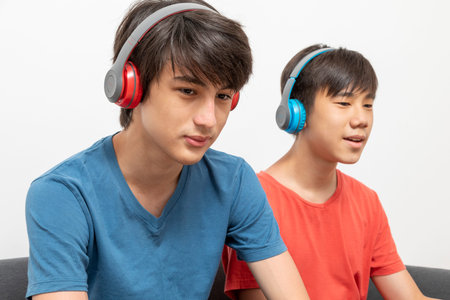 Portrait of two boys listening to music with headphones on white background