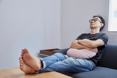 Old Asian man take a nap on grey sofa in a room.の写真素材