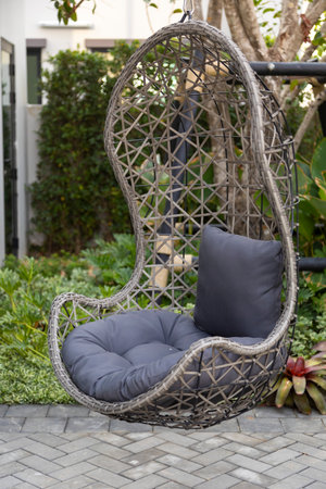 Rattan wicker cocoon garden swing chair hanged on frame. Recreation scene with a hammock-chair in the backyard of the house. Relax concept with hammock chair .の写真素材