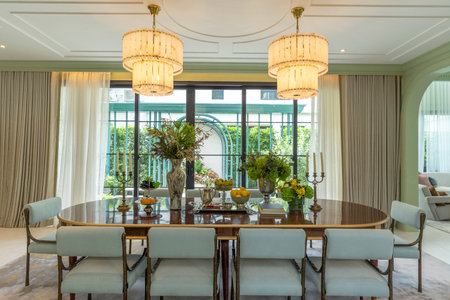 Beautiful luxurious traditional style dining room with bouquets of flowers on the table. Elegance dinning table with luxurious pendant.の写真素材