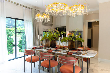 Beautiful luxurious traditional style modern dining room with bouquets of flowers on the table. Elegance dinning table with luxurious pendant.の写真素材