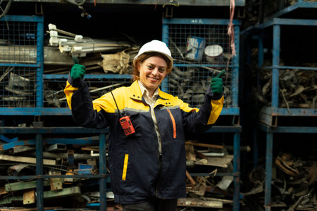 Portrait of a female worker at the factory. She is wearing a safety helmet and gloves.
