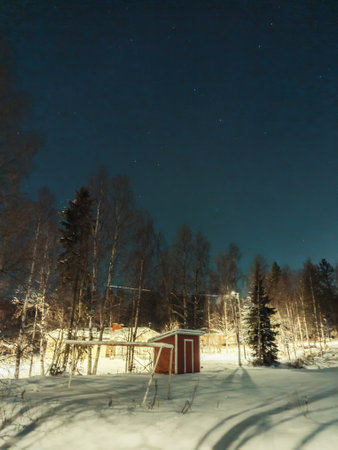 Red hut in snow in forest below starry sky in Rovaniemi, Laplandの写真素材
