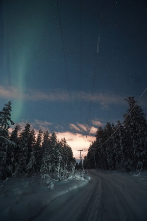 Faint aurora above snowmobile tracks and power lines in Rovaniemi, Laplandの写真素材