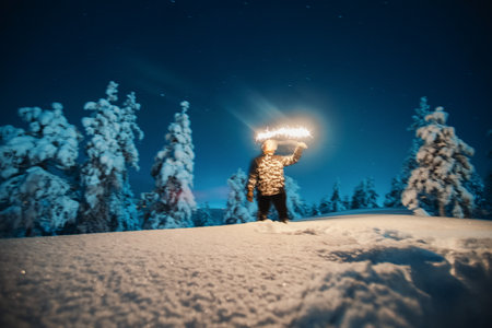 Man with sparkler in winter wonderland at night in Rovaniemi, Laplandの写真素材
