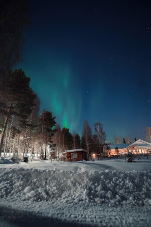 Green northern lights over snowy garden and shed in Rovaniemi, Laplandの写真素材