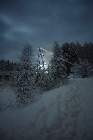 Light on snowy wooden bridge in forest in polar night in Rovaniemi, Laplandの写真素材