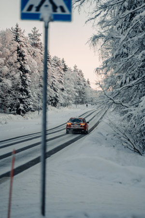 Car driving down icy road between snowy trees in Rovaniemi, Lapland in winterの写真素材