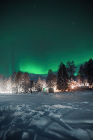 Strong green northern lights in starry sky over house in Rovaniemi, Laplandの写真素材
