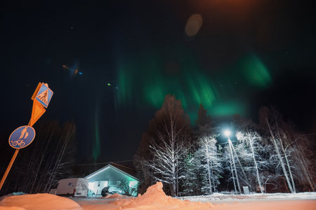 Strong green aurora borealis over house in snowy forest in Rovaniemi, Laplandの写真素材