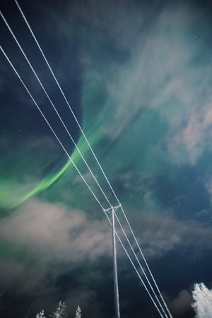 Aurora borealis in sky behind faint clouds in Rovaniemi, Laplandの写真素材