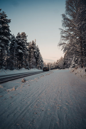 Car driving down icy road through snowy forest in Rovaniemi, Laplandの写真素材