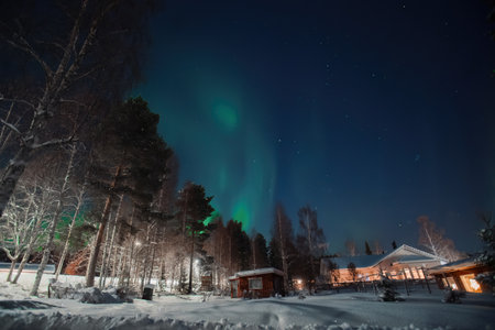 Aurora over red wooden shed in snowy garden in Rovaniemi, Laplandの写真素材