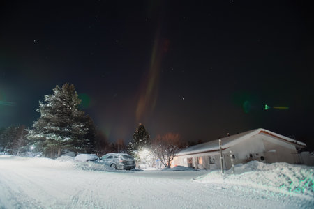Strip of purple aurora borealis over car and houses in Rovaniemi, Laplandの写真素材
