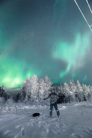 Man stood with arms out under the northern lights in Rovaniemi, Laplandの写真素材