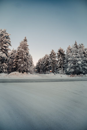 Turning out of snowy forest onto main road in Rovaniemi, Lapland in winterの写真素材
