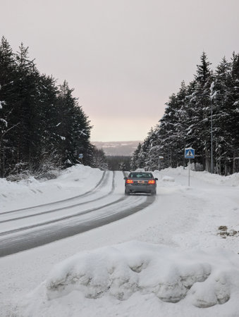 Car driving down icy road through snowy Lapland wilderness in Rovaniemiの写真素材