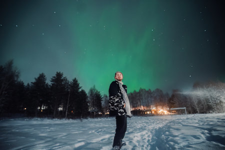 Man stood in snowy field under northern lights in Rovaniemi, Laplandの写真素材