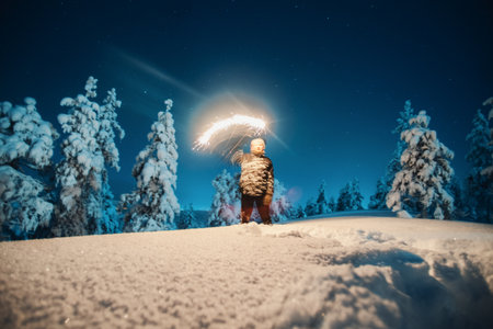 Man with sparkler in the snow at night in forest in Rovaniemi, Laplandの写真素材