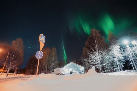 Strong aurora borealis over house in snowy trees in Rovaniemi, Laplandの写真素材