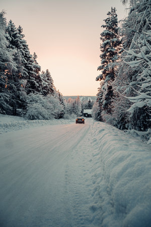 Car driving down icy road through snowy forest in Rovaniemi, Lapland in winterの写真素材