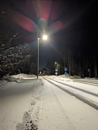 Snowy road through Rovaniemi at night under streetlight in Laplandの写真素材