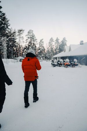 Man in red coat walking towards snowmobiles in Ranua, Lapland in winterの写真素材