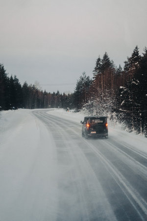 Car on road through snowy Lappish forest in Ranua, Laplandの写真素材