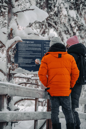 Couple reading sign in snowy forest in Ranua, Laplandの写真素材