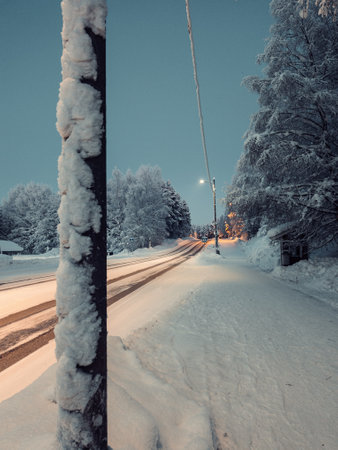 Snowy road under powerlines at dusk in Rovaniemi, Lapland in winterの写真素材