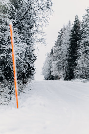 Red pole next to snowy road in Rovaniemi, Lapland in winterの写真素材