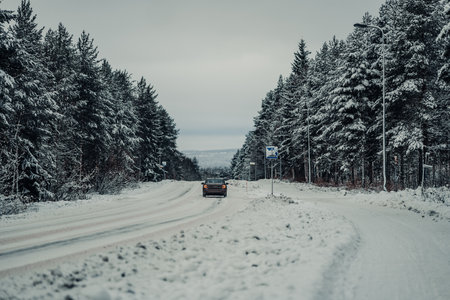 Car on snowy street outside of Rovaniemi in winter in Laplandの写真素材