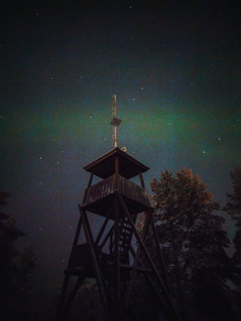 Aurora above snowy Syvasenvaara lookout tower in Rovaniemi, Lapland in winterの写真素材